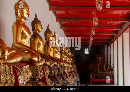 Una fila di Buddha dorati seduti a Wat Pho, Bangkok, Thailandia. Foto Stock