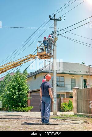 elettricista in una torre per auto per riparare le linee elettriche Foto Stock