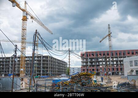 Gru di costruzione vicino agli edifici non finiti. Costruzione e sviluppo di nuovi distretti Foto Stock