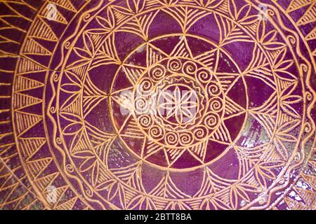 Modello tradizionale di ceramica tegola mandala ciotola. Colori dorati e viola, primo piano Foto Stock