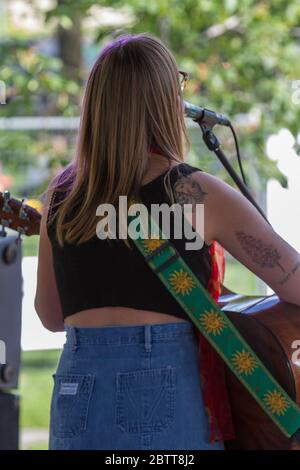 Bella femmina, in concerto all'aperto, con tttoo su braccio e spalla, girato da dietro. Foto Stock