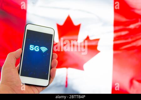 Una persona che tiene uno smartphone con un cartello 5G su sfondo bandiera canadese Foto Stock