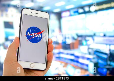 Kennedy Space Center, Florida, Stati Uniti. 27 maggio 2020. Una persona che ha un iPhone con il logo della NASA con un lancio del controllo missione fuori fuoco Foto Stock