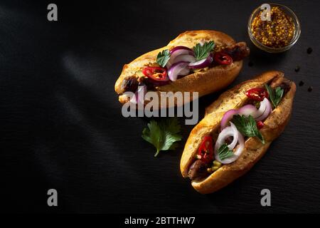 Due deliziosi hot dog su sfondo di pietra scuro. Vista dall'alto Foto Stock