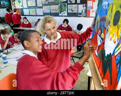 SCUOLA D'ARTE PITTURA EASEL ragazza e ragazzo giovane junior 12-14 anni gli studenti adolescenti si divertono a lavorare insieme su un progetto di pittura ad olio in una scuola d'arte Foto Stock