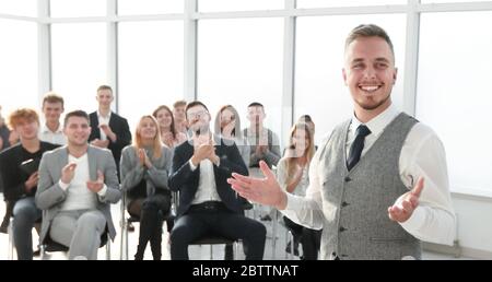 un diffusore sorridente davanti a un pubblico applaudente Foto Stock