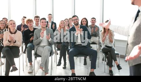 un diffusore sorridente davanti a un pubblico applaudente Foto Stock