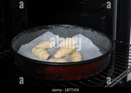 Panini non cotti in casseruola e pronti per essere appoggiati in forno. Il processo di preparazione di dolci fatti in casa. Cibo domestico e fatto a mano Foto Stock