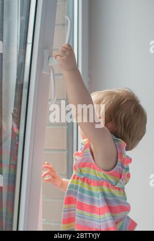 La bambina apre la finestra. Sicurezza dei bambini a casa. Prevenzione di incidenti in caduta Foto Stock