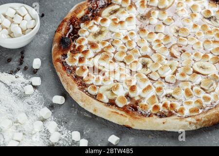 Banana caramellate con pizza spalmata di nocciole. Gli ingredienti sono pasta per pizza, Banana a fette e nocciole spalmate. Dolce e croccante Foto Stock