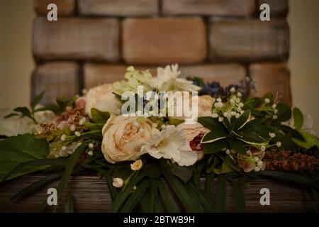 Bouquet orizzontale decorativo di fiori sul pannello sottostante su sfondo in mattoni. Foto Stock