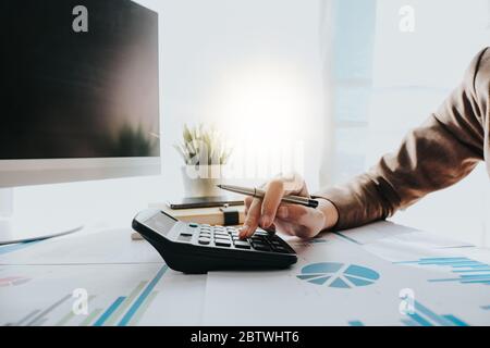 Primo piano di Business Woman o contabile utilizzando la calcolatrice durante l'analisi su carta dei dati Foto Stock