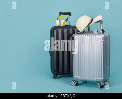 Due bagagli da viaggio con cappello e occhiali da sole isolati su sfondo blu con spazio per la copia, sfondo Travel Concept Foto Stock