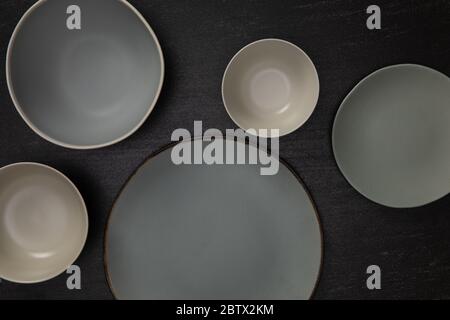 Gruppo di ciotole e piatti rotondi in ceramica vuota su pietra nera, vista dall'alto del concetto di utensili artigianali tradizionali Foto Stock