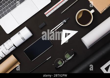 Piano creativo di architetti tavolo nero con le bozze del rotolo, piano di progetto architettonico, strumenti di ingegneria, forniture per ufficio, computer portatile e. Foto Stock
