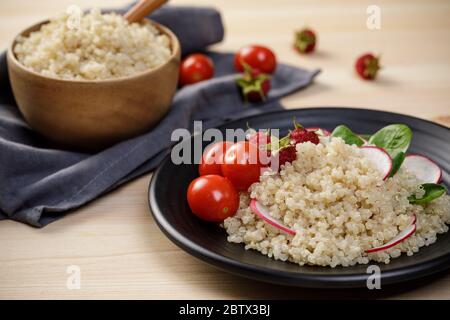 Insalata di quinoa con verdure, lampone e pomodori sul tavolo di legno. Super cibo per una dieta sana e bilanciata Foto Stock