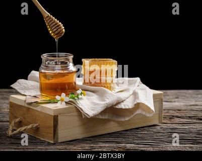 Ape di miele in vaso e nido d'ape con cucchiaia di miele e fiore su tavola di legno, prodotti di ape da ingredienti naturali biologici concetto, spazio di copia per il vostro Foto Stock