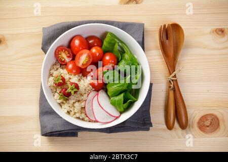 Insalata di quinoa con verdure, lampone e pomodori sul tavolo di legno. Super cibo per una dieta sana e bilanciata Foto Stock