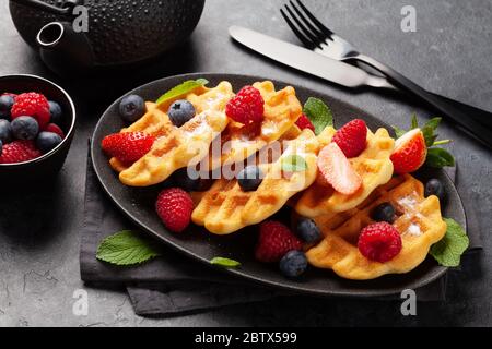 Deliziosi waffle belgi con gelato, frutti di bosco estivi e tè per la colazione Foto Stock