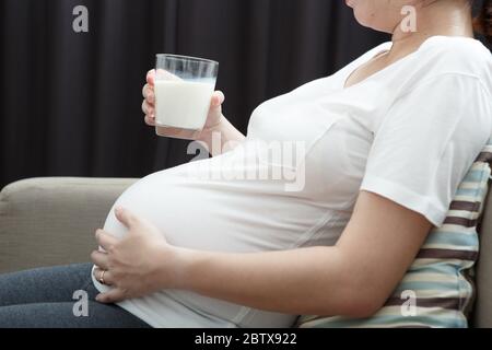 Gravidanza bere del latte nel divano a casa Foto Stock