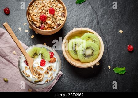 Yogurt fatto in casa con muesli, kiwi, frutta secca e frutta secca bio - semi più sani. Foto Stock