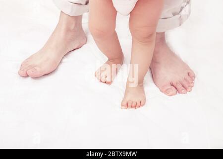 Primi passi. Bambino imparare a camminare, con l'aiuto di madri e padri. (Messa a fuoco morbida e sfocata) Foto Stock