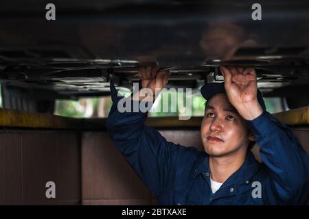 meccanico maschio con chiave per la riparazione sotto un'auto Foto Stock