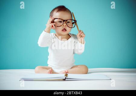 Carino ragazza asiatica del bambino che si trova sullo stomaco sul letto, studio shot Foto Stock