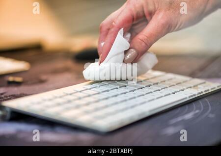 Donna pulizia mani tastiera computer, sala disinfezione. Foto Stock