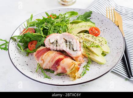 Dieta chetogena. Piatto per cena con involtino di carne di pollo, pancetta, avocado, pomodori e rucola. Disintossicazione e concetto sano. Keto alimentare. Foto Stock