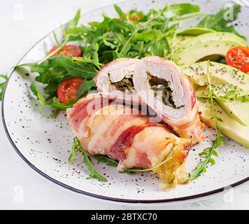 Dieta chetogena. Piatto per cena con involtino di carne di pollo, pancetta, avocado, pomodori e rucola. Disintossicazione e concetto sano. Keto alimentare. Foto Stock