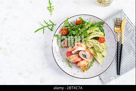 Dieta chetogena. Piatto per cena con involtino di carne di pollo, pancetta, avocado, pomodori e rucola. Disintossicazione e concetto sano. Keto alimentare. In alto, in alto Foto Stock