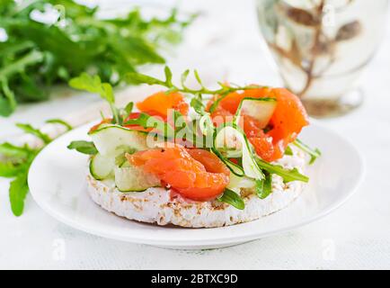 Sandwich aperto con salmone salato con croccante, formaggio spalmabile, cetriolo a fette e rucola sul piatto. Foto Stock