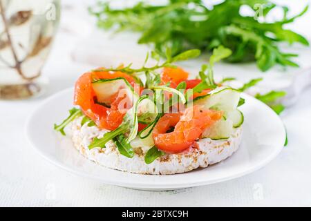 Sandwich aperto con salmone salato con croccante, formaggio spalmabile, cetriolo a fette e rucola sul piatto. Foto Stock