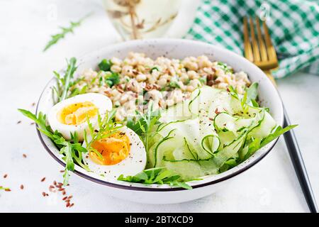 Prima colazione porridge di farinata d'avena con erbe verdi, uova sode, cetrioli e semi di lino. Cibo sano ed equilibrato. Foto Stock