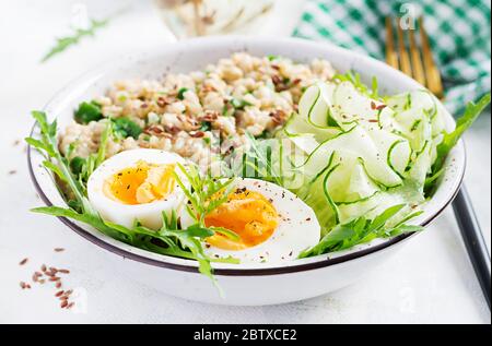 Prima colazione porridge di farinata d'avena con erbe verdi, uova sode, cetrioli e semi di lino. Cibo sano ed equilibrato. Foto Stock