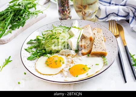 Colazione inglese - uova fritte, formaggio feta, cetriolo e rucola. Cibo americano. Foto Stock