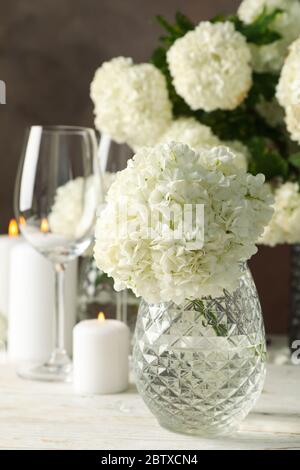 Composizione con fiori di idrangea e candele su sfondo marrone. Serata romantica Foto Stock