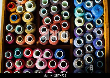 Vista dall'alto di molte bobine di fili per ricamo o cucito, sfondo colorato Foto Stock