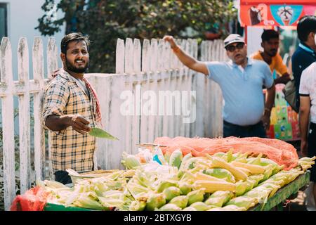 Anjuna, Goa, India - 19 febbraio 2020: Il venditore di uomo vende il mais fritto indiano tradizionale nel mercato di Anjuna. Foto Stock