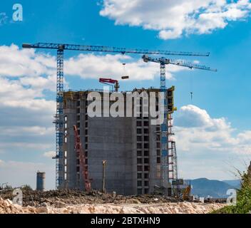 Gru industriale vicino edificio contro cielo blu con belle nuvole. Cantiere. Contesto industriale. Foto Stock