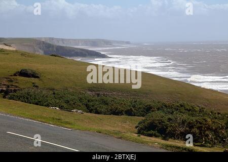 Una vista lungo le scogliere che si affacciano verso i fari di Marcross in una giornata calda e nebbiosa di mare. Foto Stock