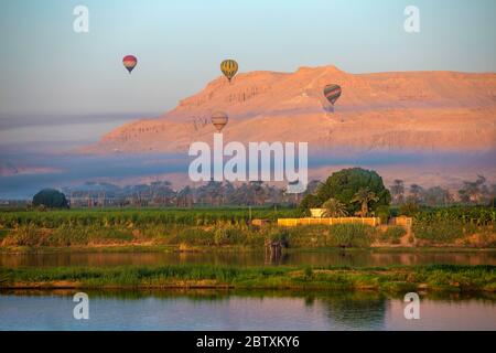 Palloncini ad aria calda che si innalzano sopra il tempio di Hatshepsut sulle rive del Nilo, vicino a Luxor, Egitto Foto Stock