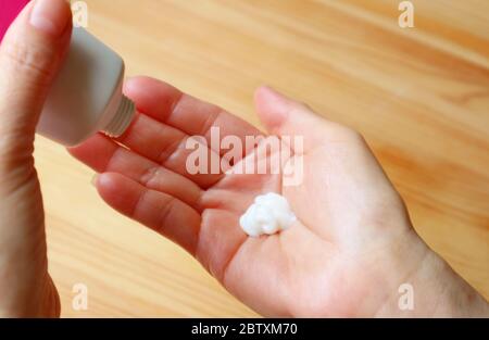 Applicare la lozione per le mani nel palmo per idratare le mani Foto Stock