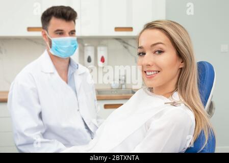 Giovane donna sorridente seduta sulla sedia presso l'ufficio dentista. Cura dentale, denti sani. Immagine ampia con spazio per la copia Foto Stock