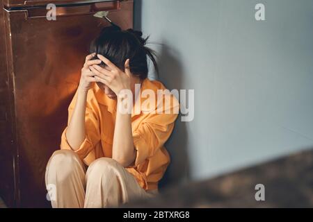Giovane donna sconvolta seduta sul pavimento a casa Foto Stock