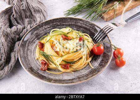 Spaghetti con agretti, una verdura di primavera italiana, e pomodori secchi con forchetta e ingredienti Foto Stock