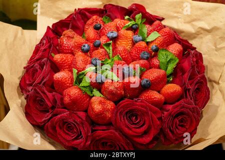 Delizioso bouquet di fragole, rose, mirtilli e foglie di menta. Primo piano Foto Stock