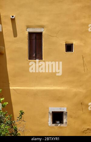 Parete e finestre colorate gialle con persiane in legno. Viaggio bellissimo sfondo pittoresco Foto Stock