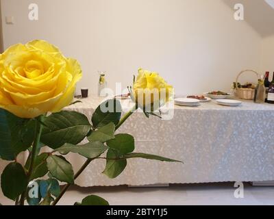 Bouquet di rose gialle e tavolo con piatti sullo sfondo Foto Stock